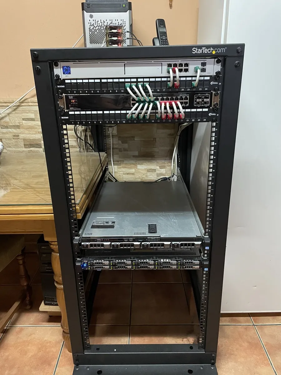Armario rack completo de suelo con electrónica de red en la parte superior y un servidor montado en la balda inferior.